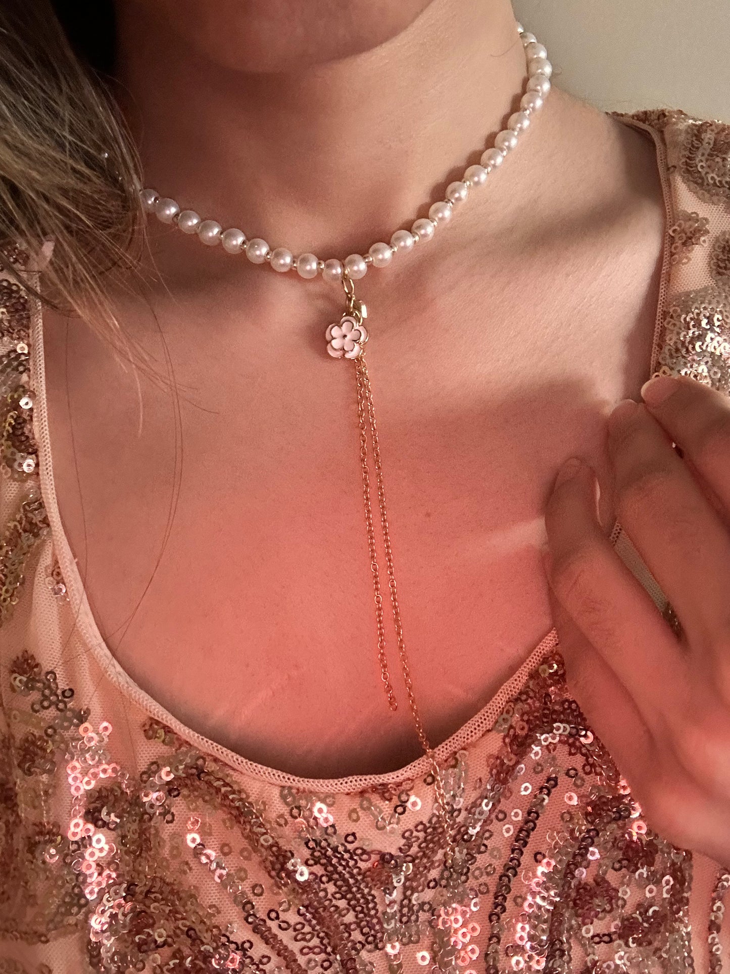 Close-up of the Emery necklace worn with a pink dress, highlighting the contrast between the pearls and the gold tassel against the soft fabric.