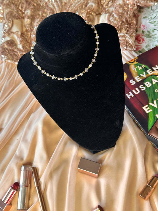 Close-up of a Faux Pearl Choker Necklace on a black velvet display, featuring golden wire and lustrous faux pearls.