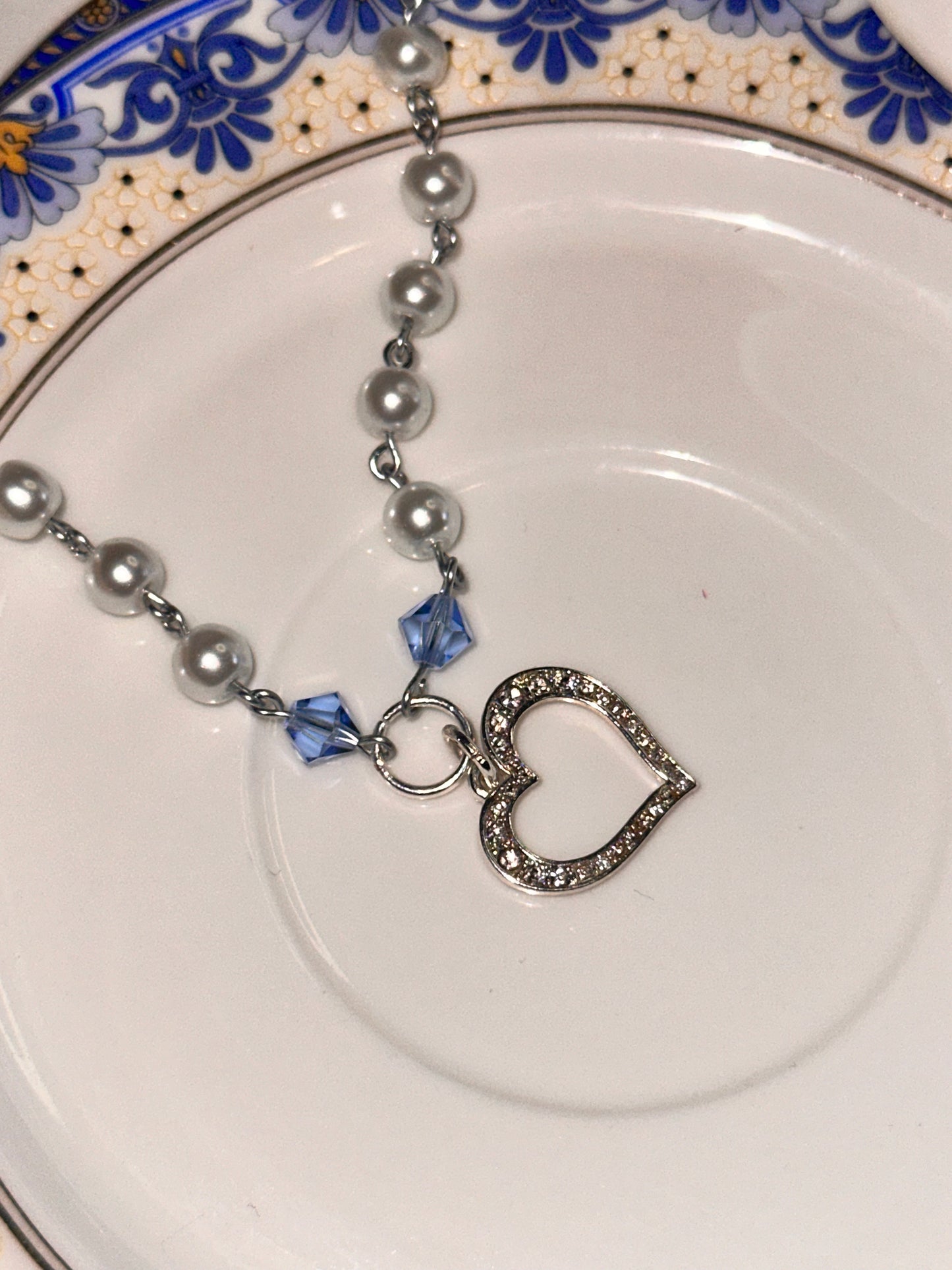 Close-up of the Cinderella Necklace with a Sterling Silver heart charm, elegantly placed on a decorative plate